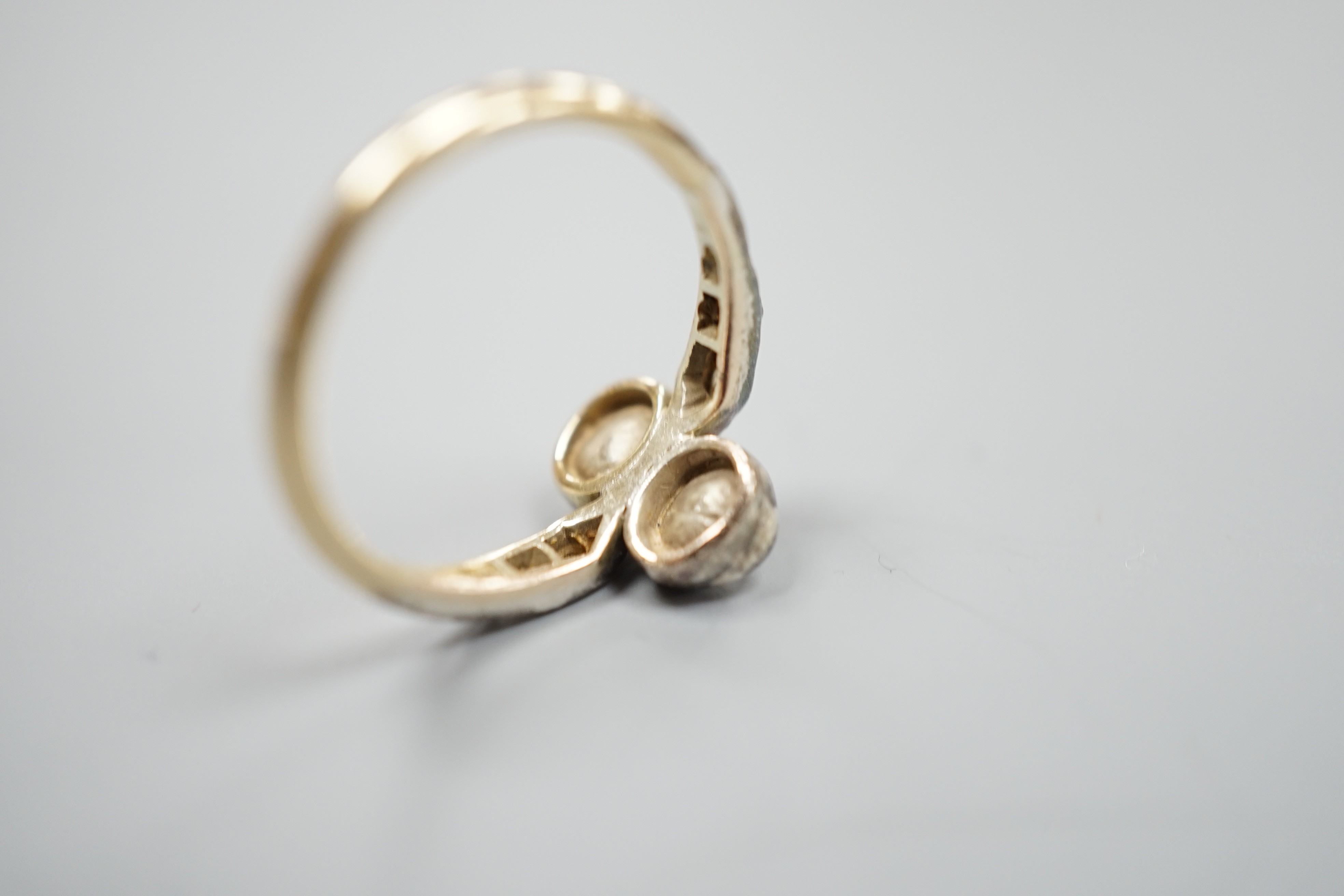 An antique yellow metal and two stone rose cut diamond set crossover ring, with diamond set shoulders, size L, gross weight 2.3 grams.